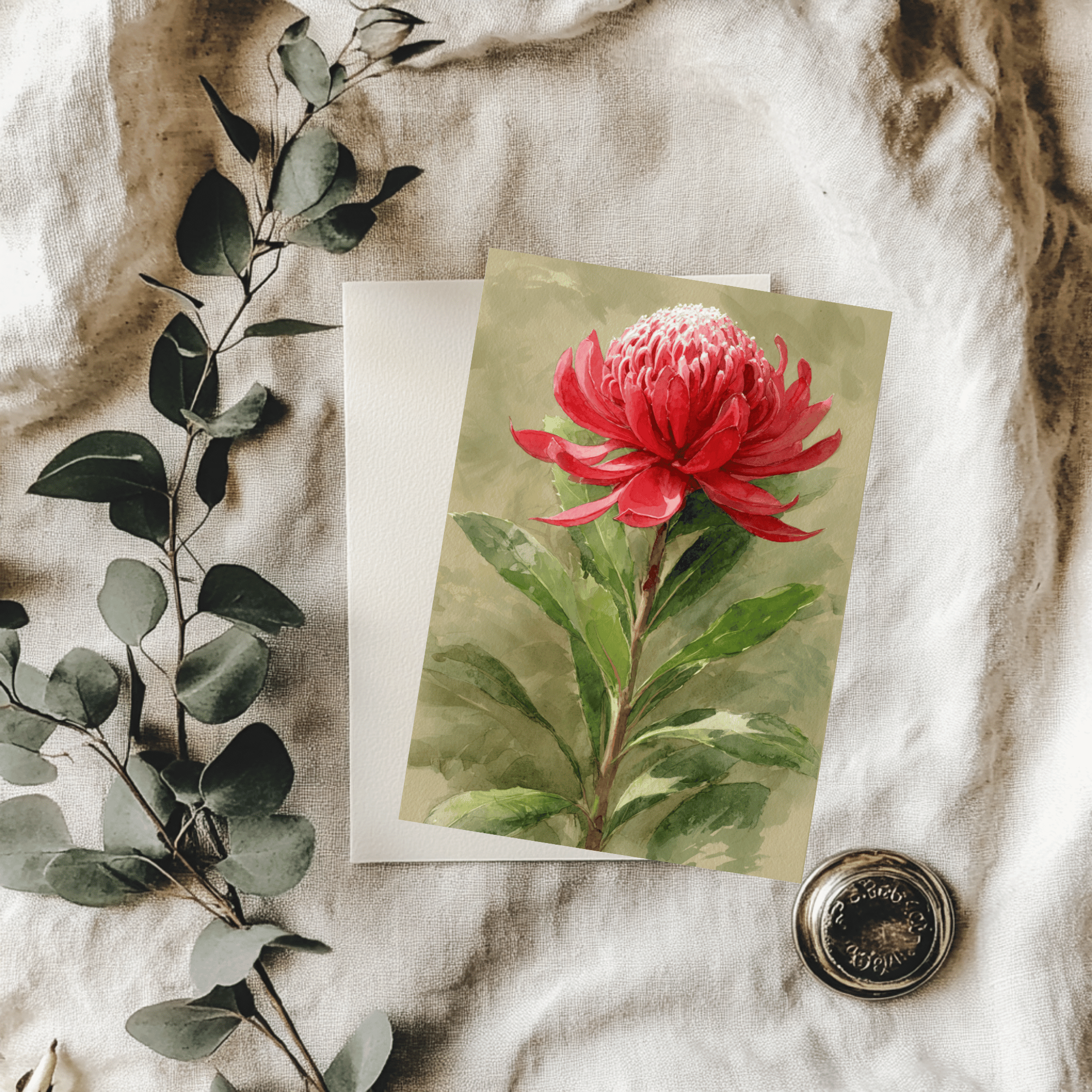 Banksia flower card on a textured fabric background with green leaves.