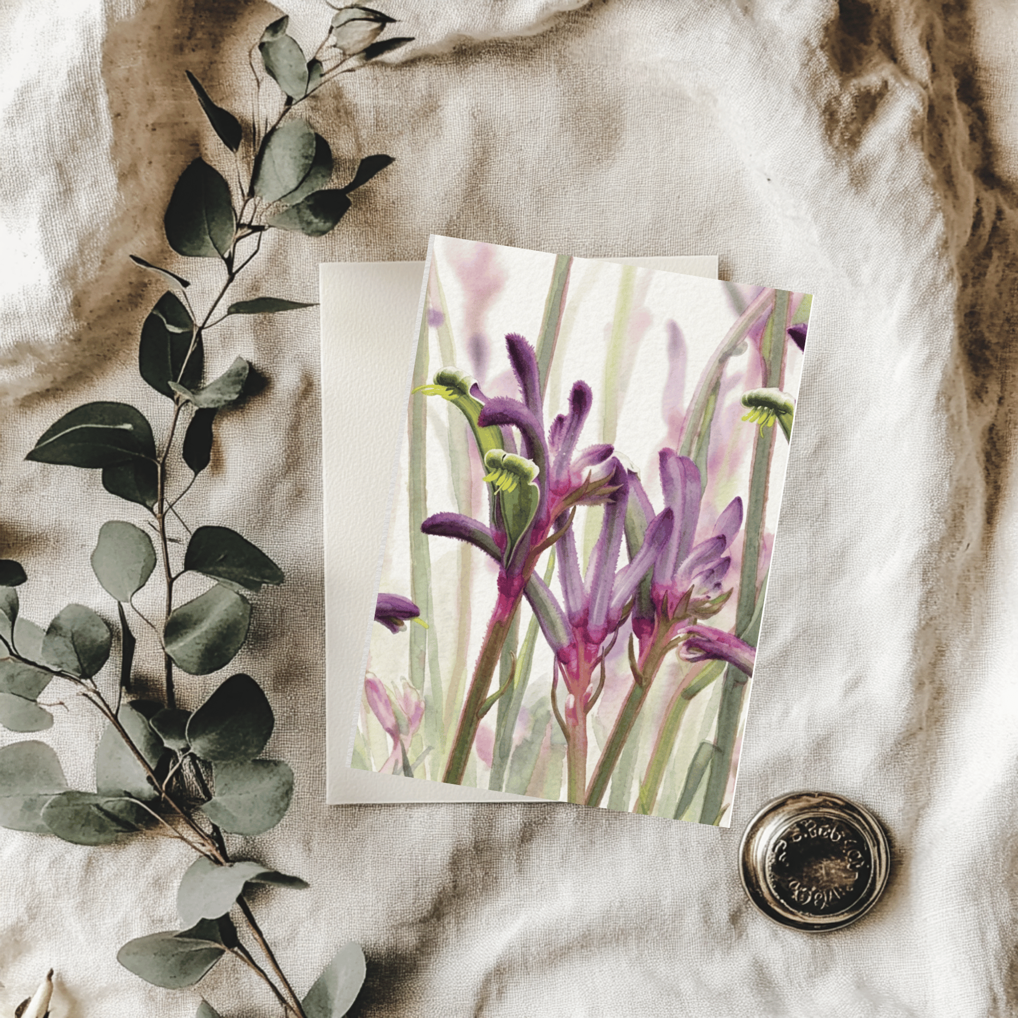 Floral card with purple flowers on a textured surface with green leaves.