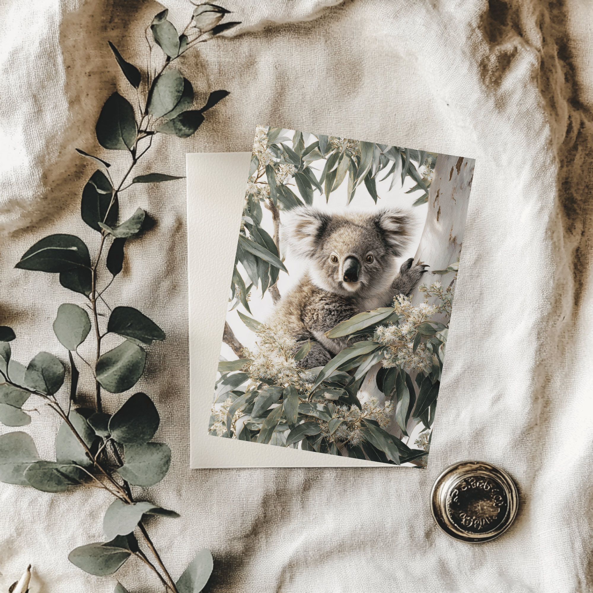 Print of a koala surrounded by eucalyptus leaves on a textured fabric background